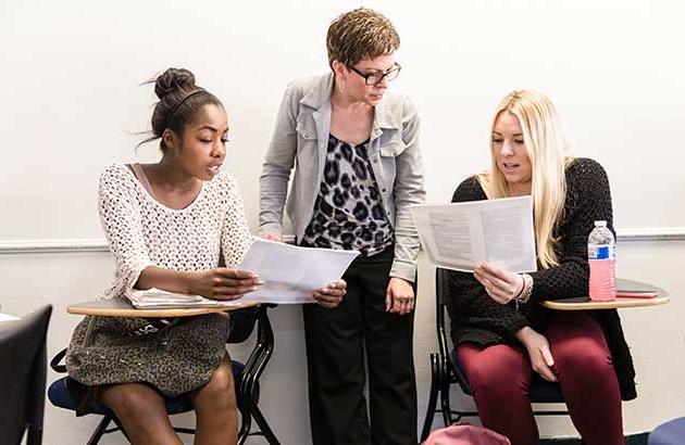 two students reviewing an assignment with a professor